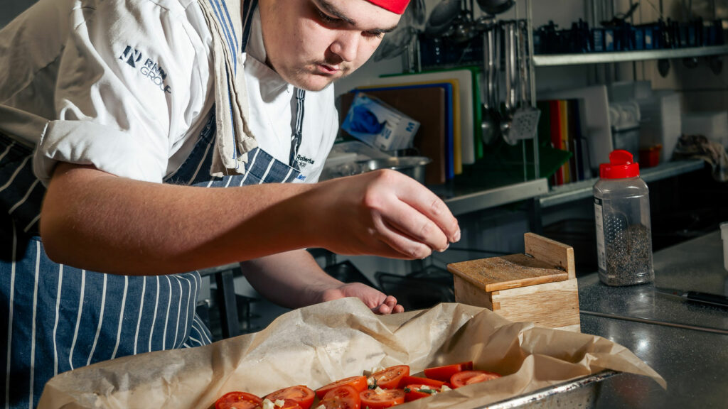 A catering student preparing food in the kitchen