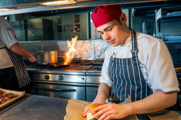 A student preparing a burger in The Wharncliffe Restaurant kitchen