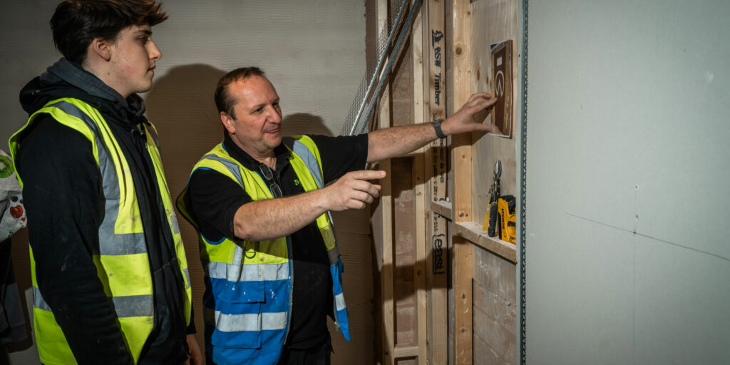 A plastering student listening to their lecturer