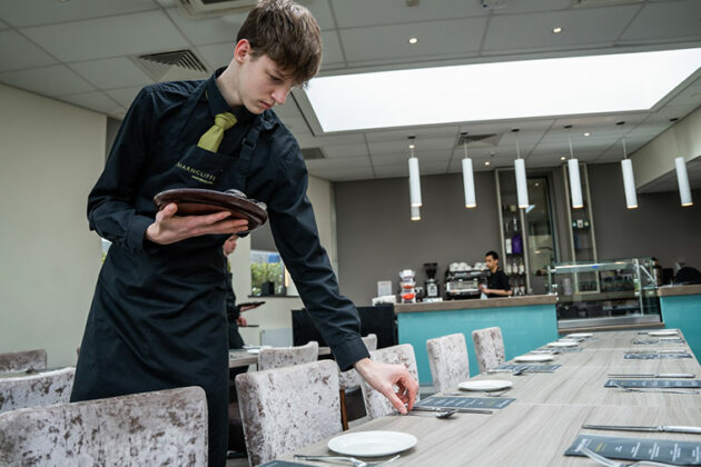 A student laying the table in The Wharncliffe