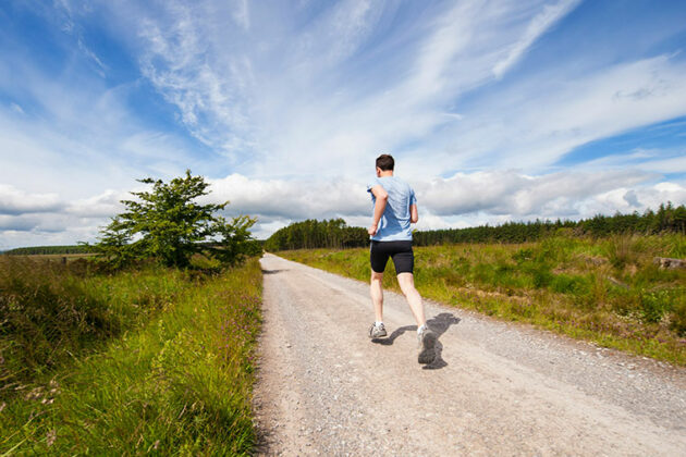 Someone jogging on a path with fields either side