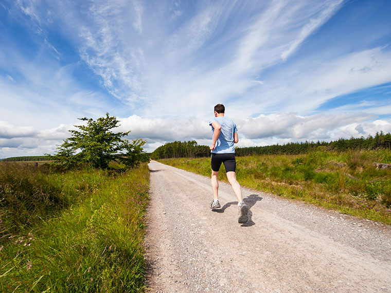 Someone jogging on a path with fields either side