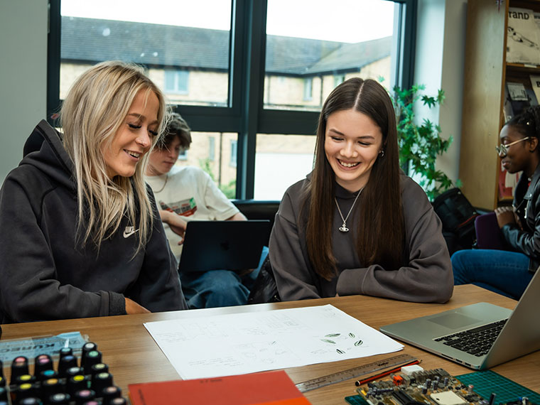 Two UCR graphic design students sat at a deskb