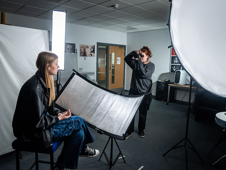 A photography student taking a photo of a fellow student