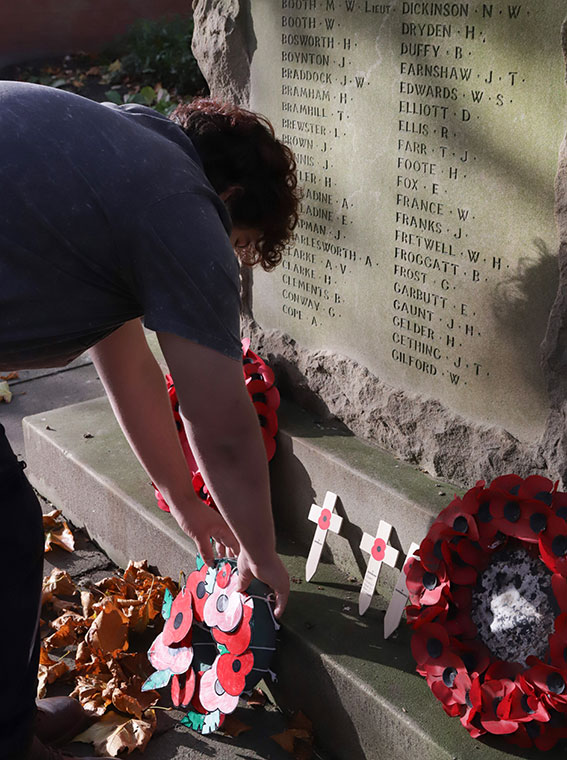 A student laying a poppy wreath at a war memorial