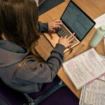 A student sat at a desk working at a laptop